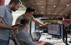 Three men looking at a computer monitor