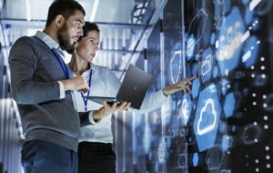 man and woman looking at data center screens